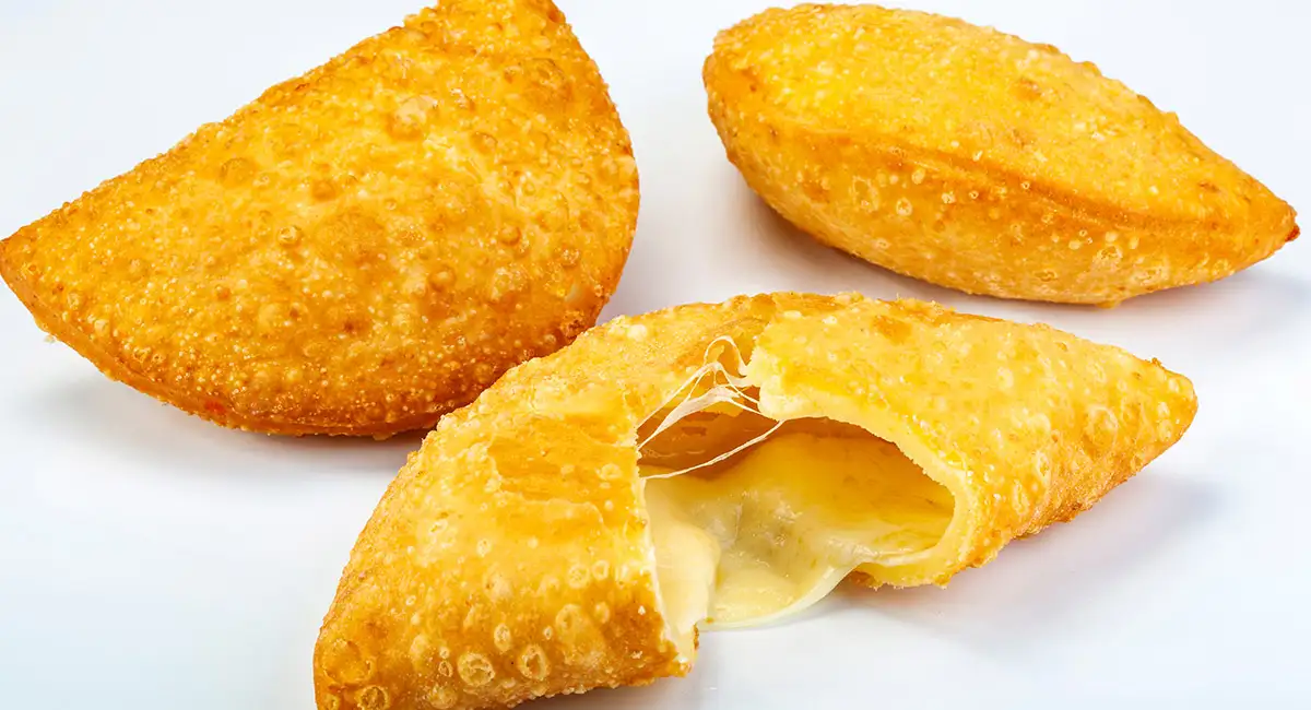 Bolivian cheese empanada with a golden crust, broken open to reveal melted queso criollo inside.